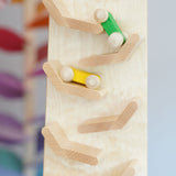 A close up of the yellow and green coloured wooden racing cars racing down the Beck Toys Cascading Tower Race Track. The cars are slightly blurred in motion. 