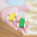 A close up of the yellow and green coloured racing car from the Beck Toys Cascading Tower Run Track set in an adult's hand.