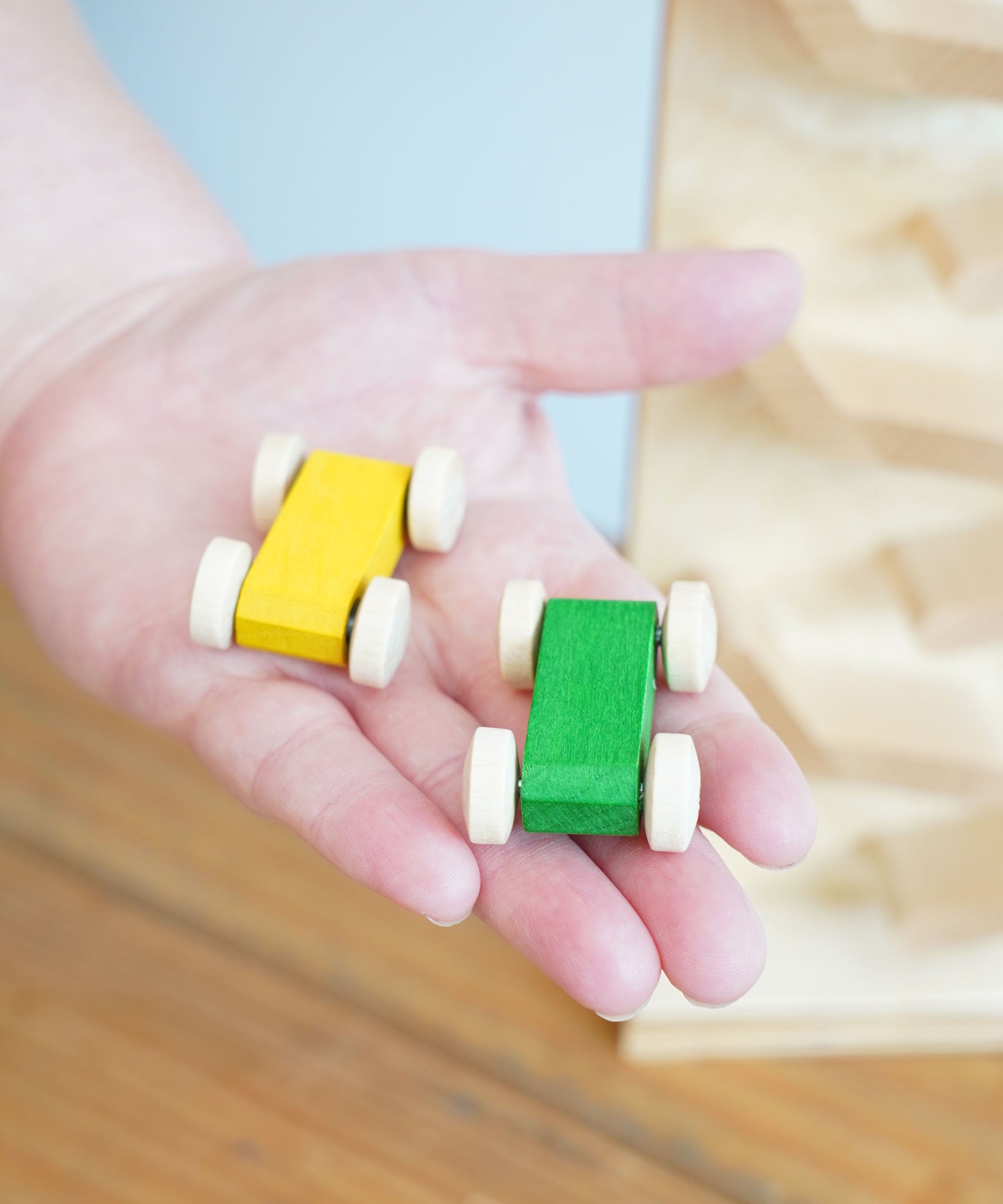 A close up of the yellow and green coloured racing car from the Beck Toys Cascading Tower Run Track set in an adult's hand.
