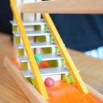 Clay marbles blurred in motion cascading down the metal glockenspiel on the Beck Toys Chimes Marble Run Track. 
