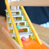 Clay marbles blurred in motion cascading down the metal glockenspiel on the Beck Toys Chimes Marble Run Track. 