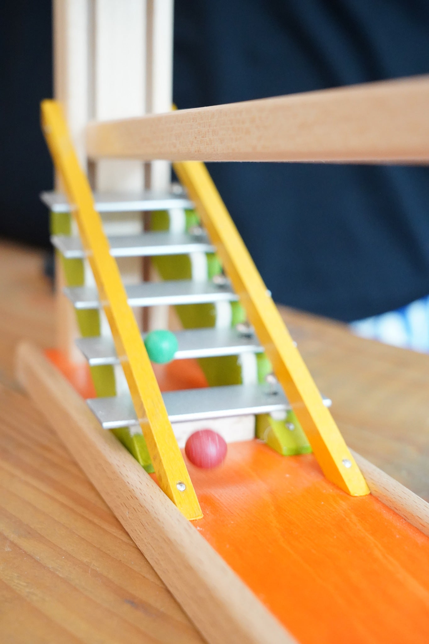 Clay marbles blurred in motion cascading down the metal glockenspiel on the Beck Toys Chimes Marble Run Track. 
