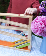 A close up of a child placing a red coloured clay marble on the Beck Toys Chimes Marble Run Track.