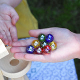 8 Beck toys coloured glass marbles in a child's hand.
