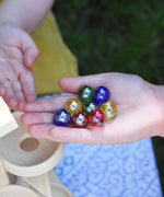 8 Beck toys coloured glass marbles in a child's hand.
