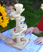 Two children playing with the Beck Marble Run Plate Tower outdoors.