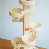 Glass marbles cascading down the Beck Toys Maple Wood Marble Run Plate Tower.
