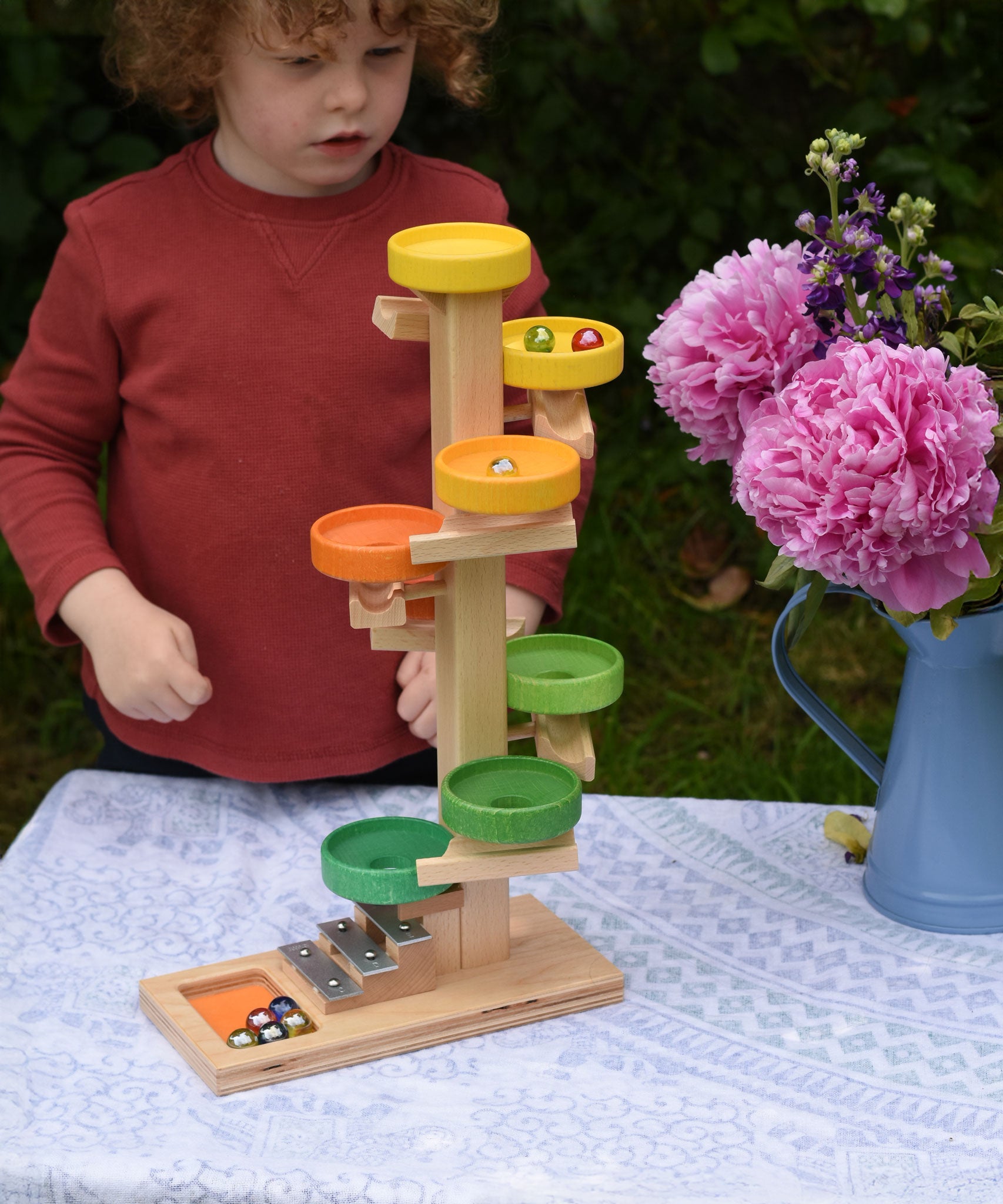 A child observing the glass marbles twirling down the Beck Toys Beech Wood Plate Tower Marble Run with Glockenspiel. 
