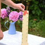 An adult placing the red coloured wooden figure on the Beck Toy Wobbler wooden tumbling toy frame. 
