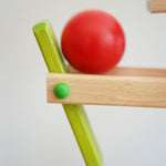A close up of the red ball on the Beck Ball Run Musical Track. The wooden ball is blurred in motion as it aces down the wooden ramps on the ball run.