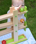 A small child placing a green coloured wooden ball on the Beck Ball Run Musical Track.