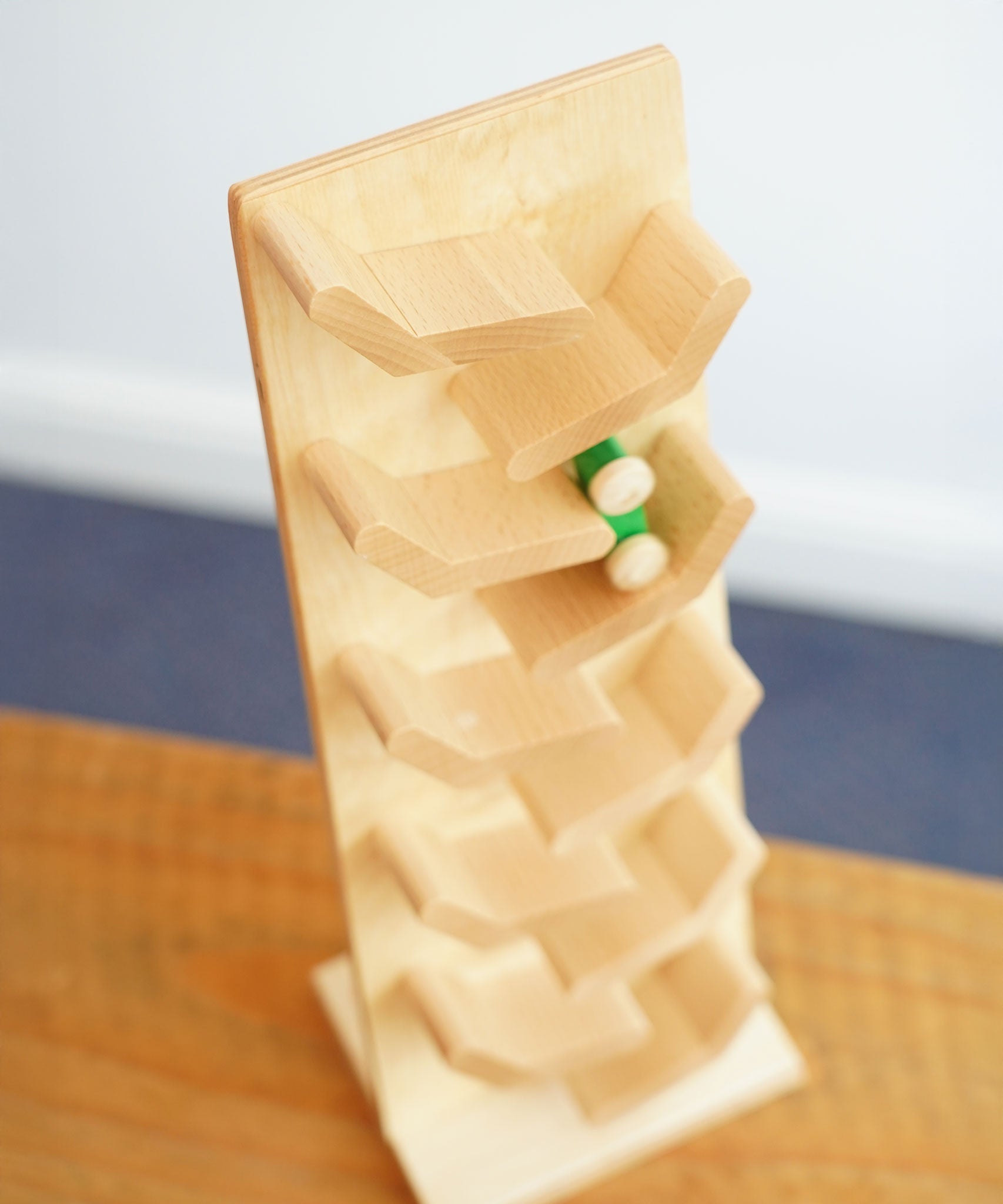 An overhead view of a green coloured wooden racing car racing down the Beck Toys beechwood cascading tower track.