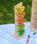 The Beck Toys Beechwood Cascading ‘Tower Running Track’ with Millipede Car Train placed on a small table outdoors. 