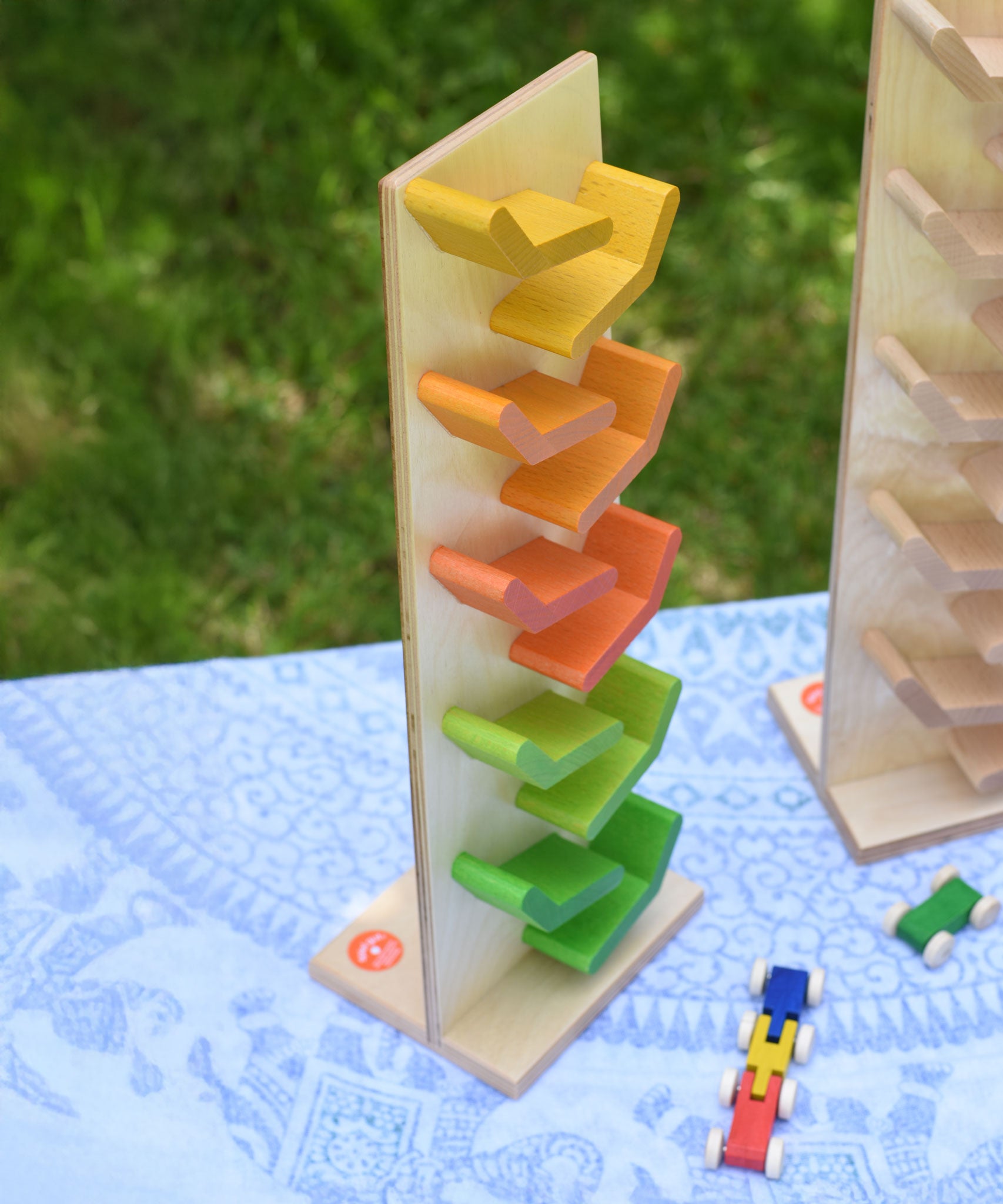 The Beck Toys Beechwood Cascading ‘Tower Running Track’ with Millipede Car Train placed on a small table outdoors. 