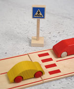 A Beck wooden pedestrian crossing  sign standing near a road set with vehicles on top 