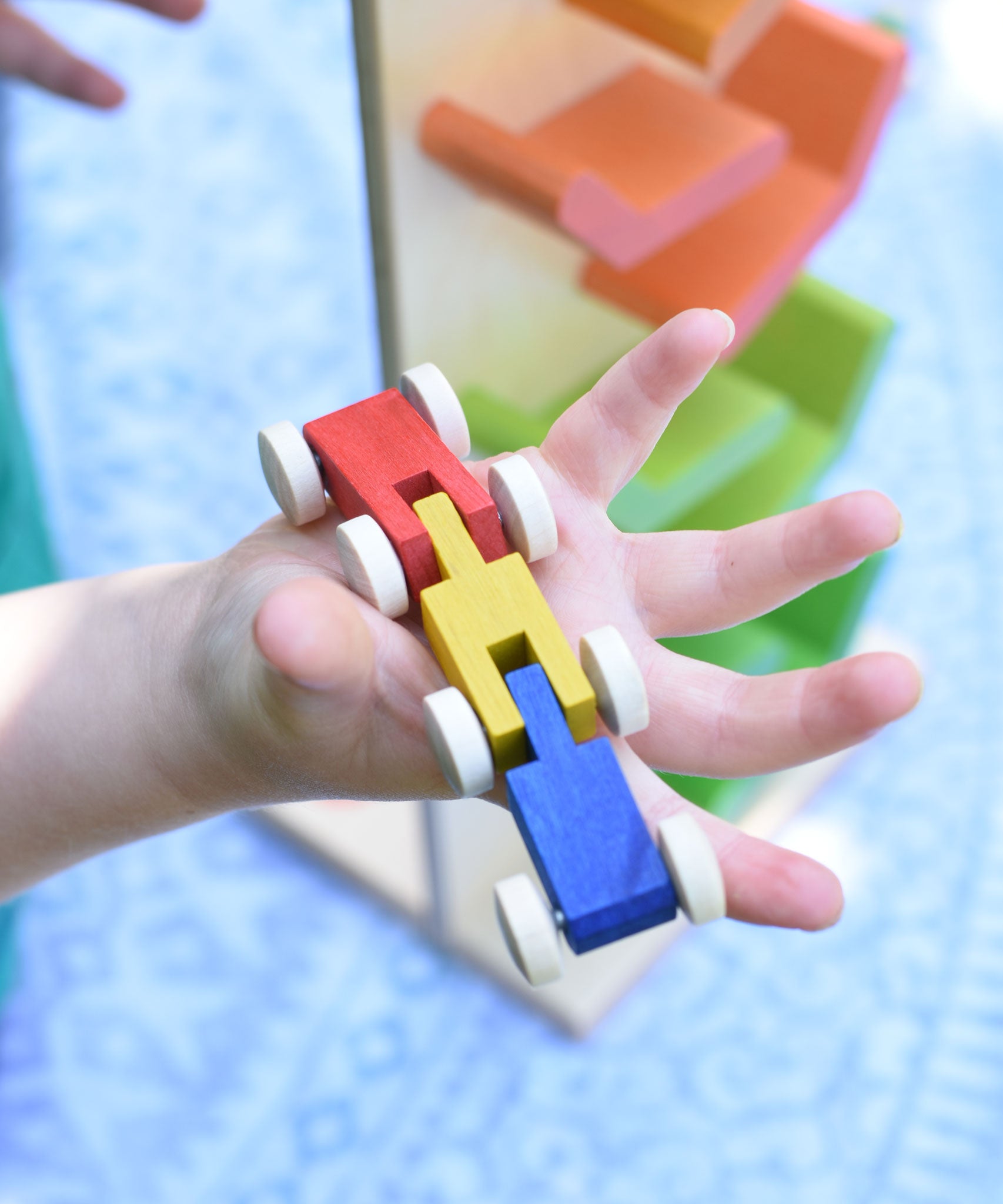 A close up of a Beck Toys wooden millipede car train toy in a child's hand. 