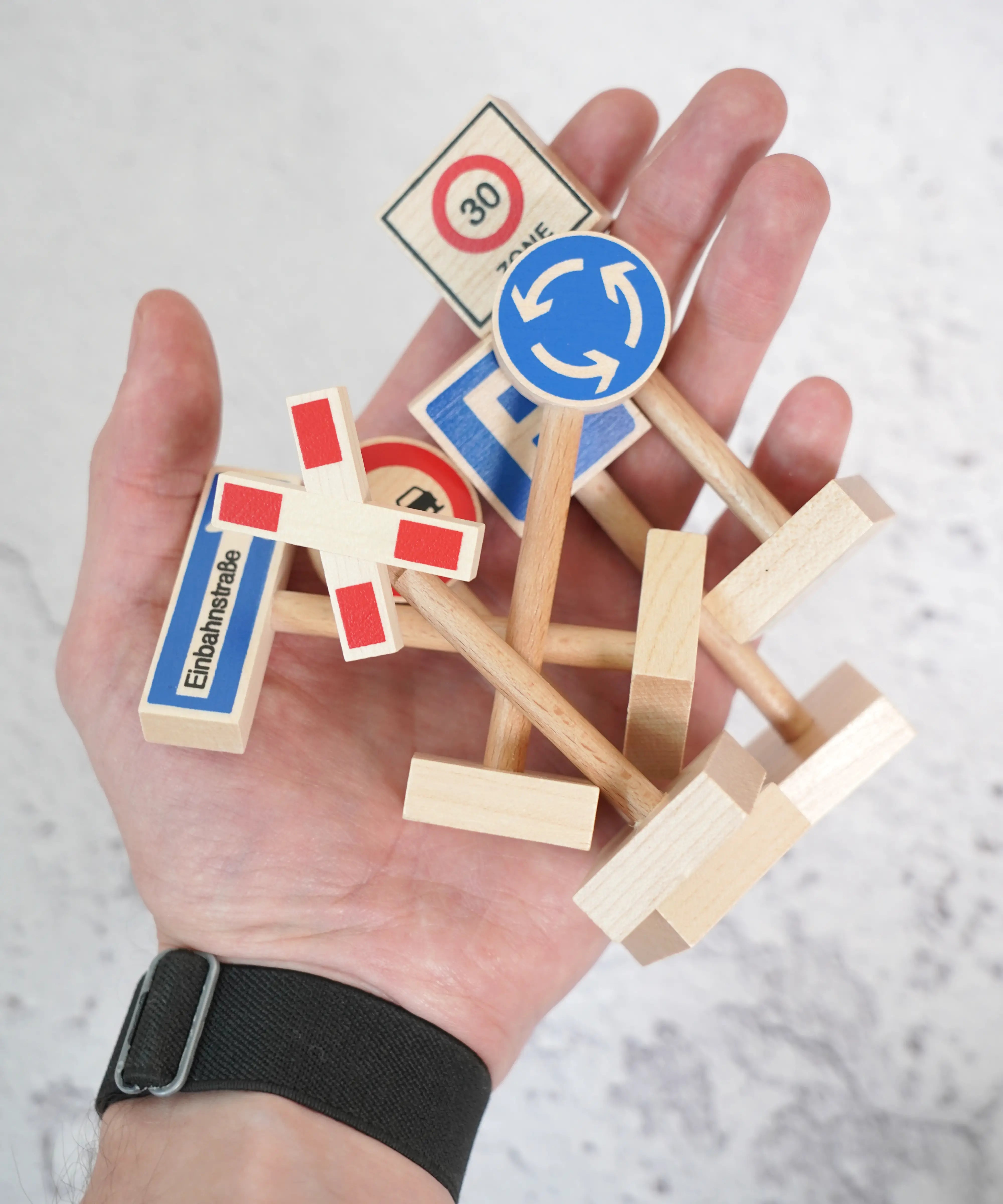An adult hand with a bunch of Beck wooden traffic showing scale