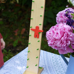 The Beck Toys Wobbler placed on a small table outdoors. The red figure can be seen in motion tumbling down the green coloured rungs. 