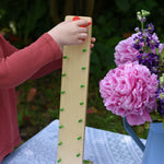 A close up of a child's hand placing the red coloured figure on the Beck Toys wooden Wobbler tumbling toy.