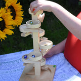 A child playing with the Beck Marble Run Plate Tower they have placed the glass marbles on the run and they can be seen cascading down the plates. 