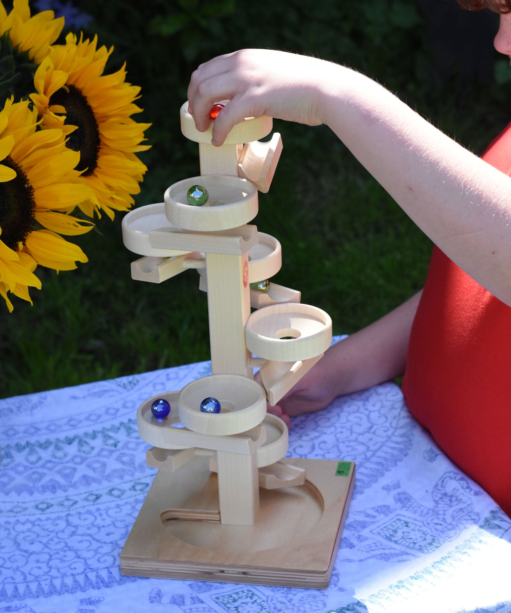 A child playing with the Beck Marble Run Plate Tower they have placed the glass marbles on the run and they can be seen cascading down the plates. 