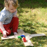 Child playing with the Beck wooden roundabout junction set, placing toy cars onto the road. 