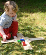 Child playing with the Beck wooden roundabout junction set, placing toy cars onto the road. 