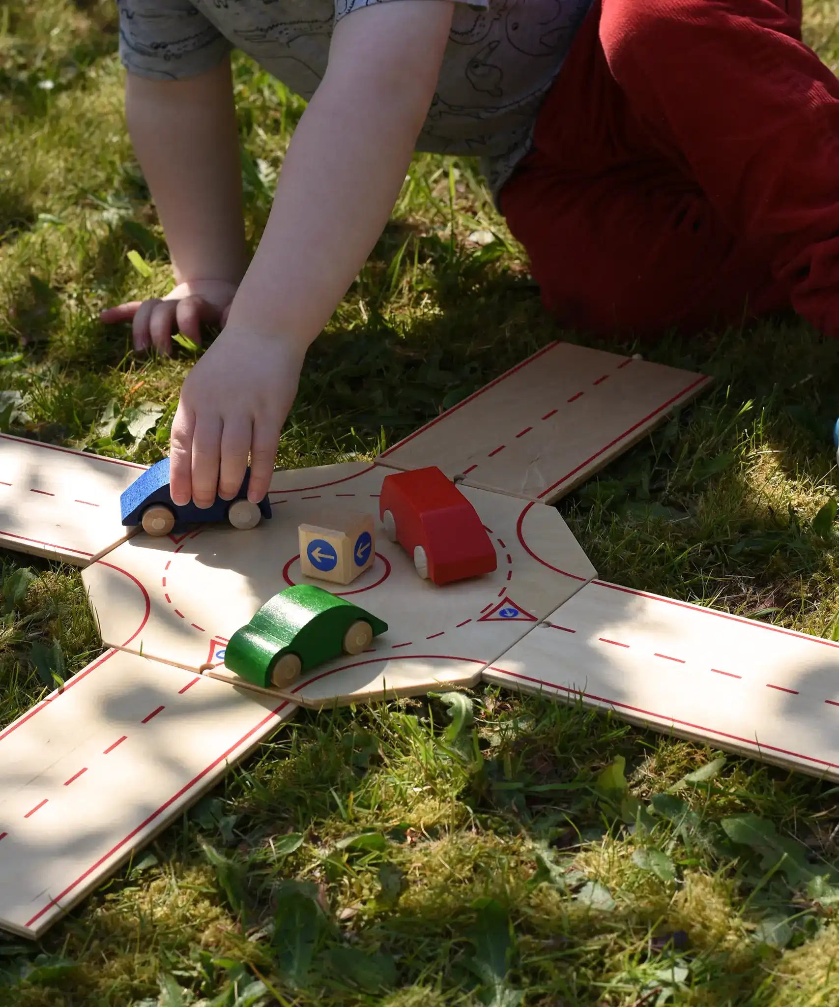 Beck wooden roundabout junction set, child placing toy cars on the roundabout. 