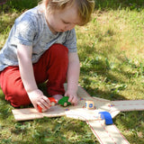 Child playing with the Beck wooden roundabout junction set, placing toy cars onto the road. 