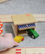 A Beck wooden toy car garage with a green coloured car half way in and a yellow one just outside. Beck have a range of wooden toys and ball runs available at Babipur. 