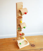 Glass marbles blurred in motion whilst cascading down the Beck Toys Beech Wood Roller Cup Marble Run.