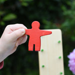 A close up of the red coloured wooden figure from the Beck Toys Wobbler tumbling toy in a child's hand.