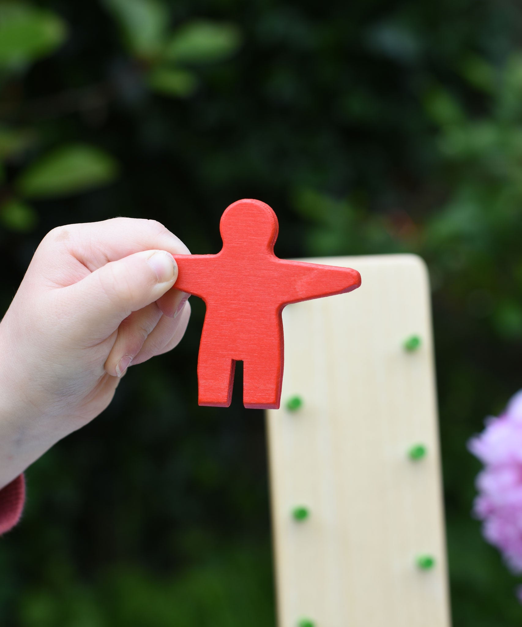 A close up of the red coloured wooden figure from the Beck Toys Wobbler tumbling toy in a child's hand.
