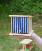 Beck wooden double garage toy in a child's hand. The blue door is closed.