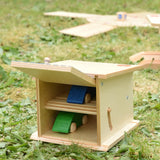 Beck wooden double garage toy with two toy cars placed inside, one on each floor. Door is shown open.