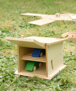 Beck wooden double garage toy with two toy cars placed inside, one on each floor. Door is shown open.