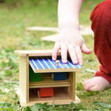 Beck wooden double garage toy played with by a child with three wooden cars paced inside.
