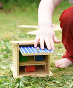 Beck wooden double garage toy played with by a child with three wooden cars paced inside.