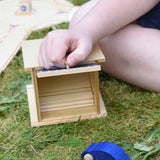 Beck wooden double garage toy placed in a small world set up. Child lifting the door by the handle.