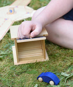 Beck wooden double garage toy placed in a small world set up. Child lifting the door by the handle.