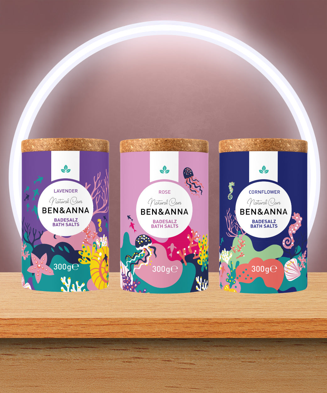 A trio of the Ben & Anna bath salts on a wooden table including a lavender rose and cornflower fragrance. 