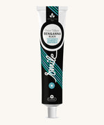 Ben & Anna certified 100% natural activated charcoal toothpaste showing a black, green and blue stripe design on the tube with a playful smile slogan in white in the middle.
