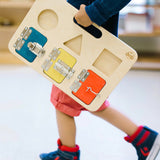 Child in red shorts walking on a white floor carrying the Big Future Toys Latch Board