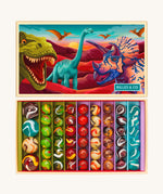 The Billes & Co large collectible glass marbles box, with a dinosaur theme. The box is open to show the different types and colours of glass marbles, next to the lid that is illustrated with colourful dinosaurs.
