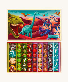 The Billes & Co large collectible glass marbles box, with a dinosaur theme. The box is open to show the different types and colours of glass marbles, next to the lid that is illustrated with colourful dinosaurs.