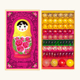 Opened decorated box of Billes & Co Katerina Matriochka doll inspired marbles in shades of pink, green and yellow