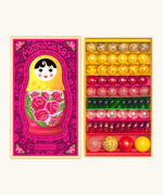 Opened decorated box of Billes & Co Katerina Matriochka doll inspired marbles in shades of pink, green and yellow