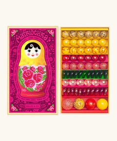 Opened decorated box of Billes & Co Katerina Matriochka doll inspired marbles in shades of pink, green and yellow