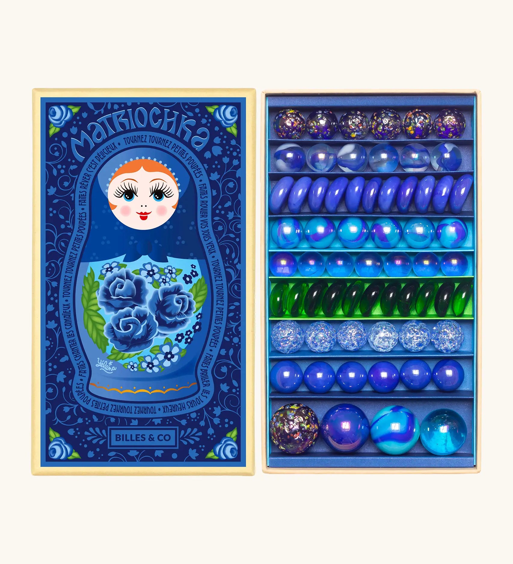 Opened decorated box of Billes & Co Yelena Matriochka doll inspired marbles in shades of blues and greens