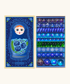 Opened decorated box of Billes & Co Yelena Matriochka doll inspired marbles in shades of blues and greens